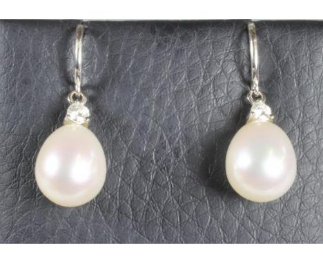 A PAIR OF PEARL DROP EARRINGS, the tear shaped white cultured pearls peg set to 18ct white gold mounts claw set with a small 