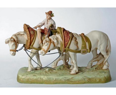 A ROYAL DUX PORCELAIN GROUP, early 20th century, modelled as a young boy wearing a hat, open necked shirt and breeches, seate