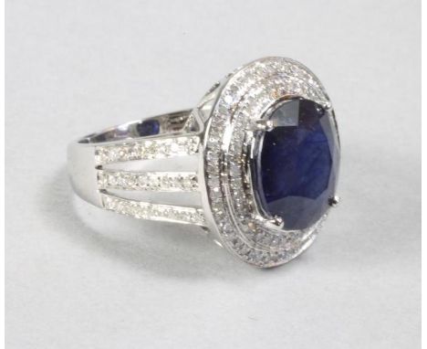 A SAPPHIRE AND DIAMOND COCKTAIL RING, the oval cut sapphire of approximately 5.60cts, claw set within double borders of brill