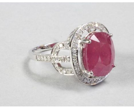 A RUBY AND DIAMOND COCKTAIL RING, the oval cut ruby of approximately 9cts, claw set within a pave diamond border to similar s