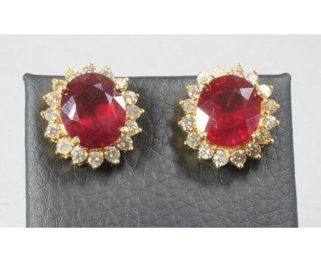 A PAIR OF RUBY AND DIAMOND EAR STUDS, the oval facet cut rubies of approximately 13cts total, each within a border of sixteen