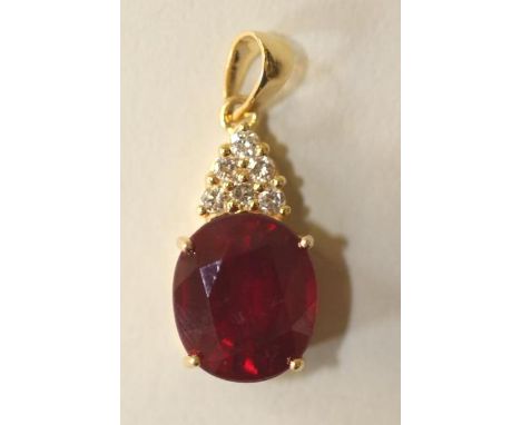 A RUBY PENDANT, the oval facet cut ruby of approximately 12.50cts claw set in 14kt gold, below a triangular panel pave set wi