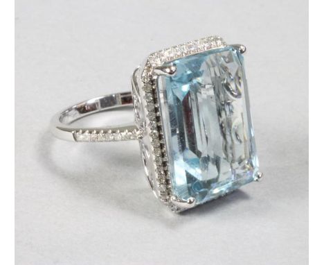 AN AQUAMARINE COCKTAIL RING, the emerald cut stone of approximately 15cts claw set within a pave diamond canted border with b