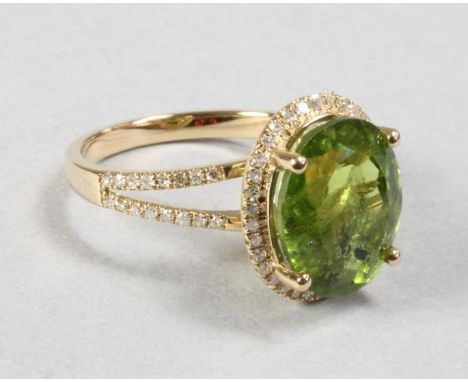 A PERIDOT AND DIAMOND DRESS RING, the oval cut peridot of approximately 5.70cts, claw set within a pave diamond border and si