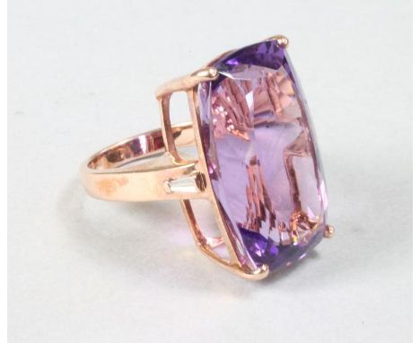 AN AMETHYST COCKTAIL RING, the facet cut cushion stone claw set to plain shoulders each set with a small baguette diamond to 