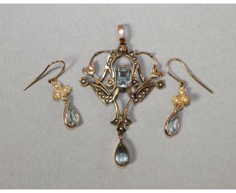 AN EDWARDIAN 9CT GOLD PENDANT, the open shield panel centred by a cushion cut aquamarine and hung with a similar tear cut sto