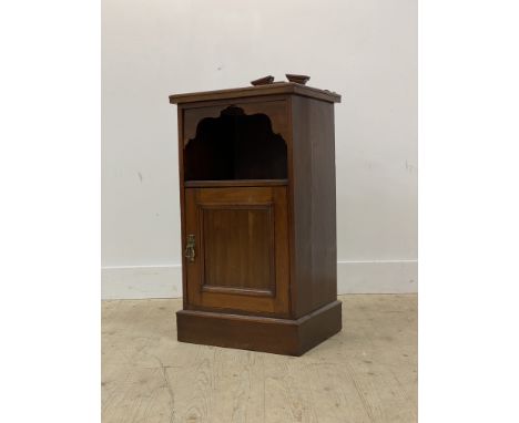 An early 20th century walnut bedside cabinet, with raised back over open shelf and panelled cupboard door, raised on a skirte