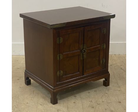 A Chinese style stained hardwood bedside cabinet, fitted with two panelled doors enclosing a shelf, raised on bracket support