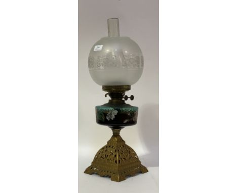 An Edwardian oil lamp, the cast brass base supporting a green glass reservoir hand enamelled with floral sprays, complete wit