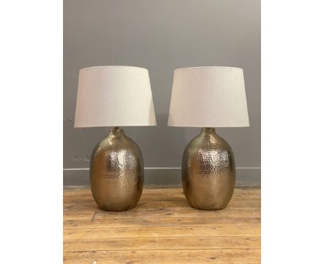 A pair of contemporary planished metal lamp bases, each complete with an oatmeal linen shade. H60cm.&nbsp;