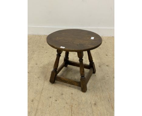 An 18th century style oak lamp table, the circular top raised on turned and block supports united by stretchers. H45cm, D50cm