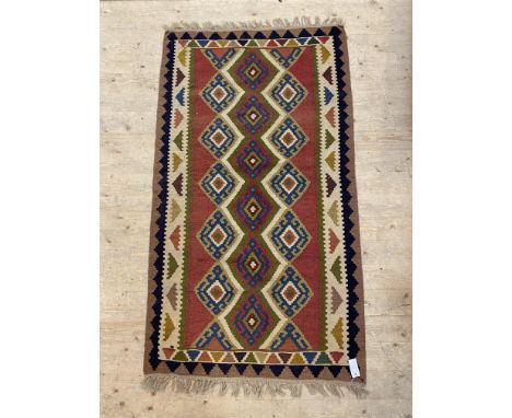 A vintage kilim rug, the red field with geometric pole medallion within a border having a repeating chevron motif. 186cm x 10