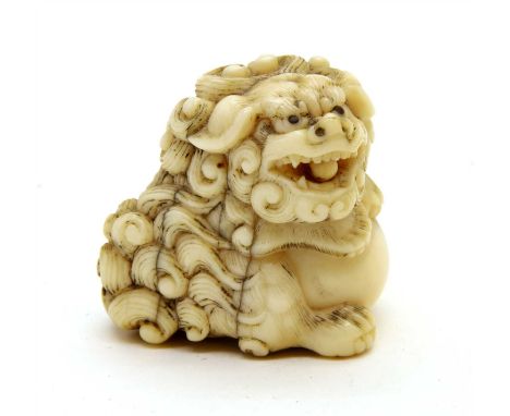 A Japanese ivory netsuke, c.1900, of a Buddhist lion