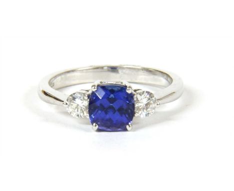 An 18ct white gold three stone tanzanite and diamond ring, a cushion cut tanzanite with a stated weight of 1.35ct, four claw 