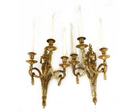 A pair of gilt brass three-branch wall lights, each with flaming urn finial, laurel swags and ram's head decoration, 35cm wid