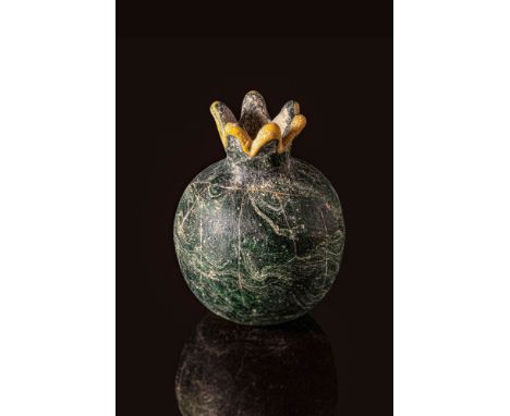 New Kingdom, Dynasty 18th - 19th, Ca. 1550 - 1190 BC. A glass pomegranate votive vessel with a globular dark green body marbl