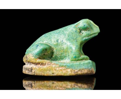 Late Period - Ptolemaic Period, Ca. 664 - 30 BC. A pale green faience amulet in the form of a crouching frog, modelled in the