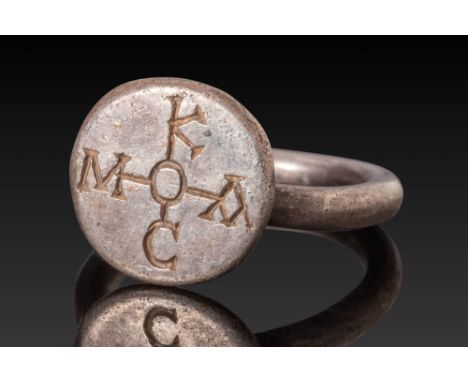 Ca. AD 600. A silver ring with a flat circular bezel engraved with a symmetrical Greek inscription arranged in the form of a 