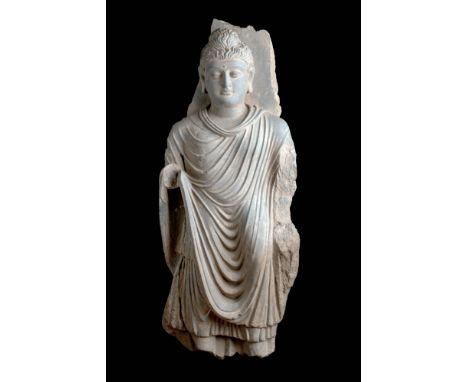 Ca. AD 200 - 300.A grey schist statue of Buddha standing with his left leg slightly extended and a bent knee, adorned in a ka