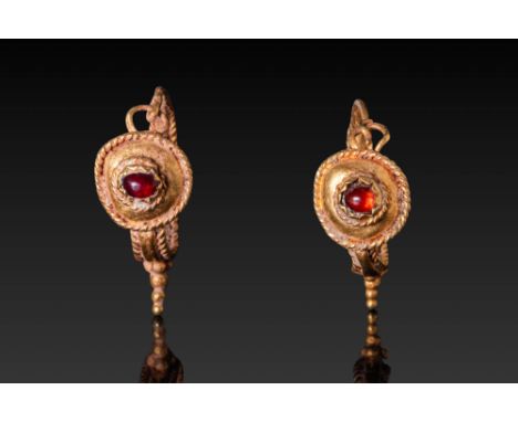 Ca. 100 BC - AD 200. A matched pair of gold earrings, each centred with a garnet cabochon in a circular cell enclosed by a tw