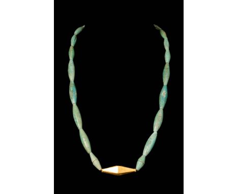 Ca. 1550 - 664 BC. A restrung necklace of elongated turquoise-blue faience beads centring on a faceted bicone-shaped gold bea