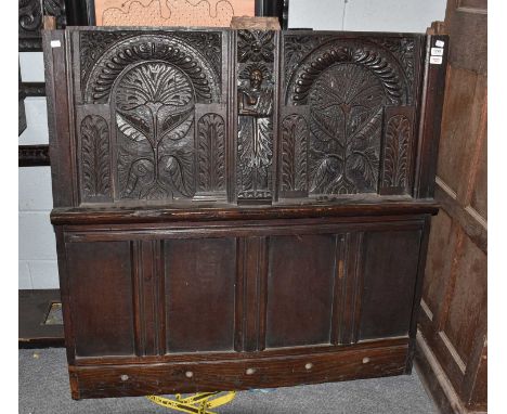 A 17th century carved oak panel, possibly a headboard, decorated with stylised trees within arches centred by a figure, 120cm