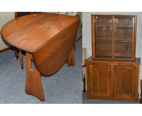 An Ercol elm glazed bookcase on an associated elm cupboard base, 114cm by 49cm by 179cm, together with a an Ercol style elm d