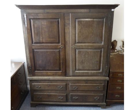 A large mid-18th century oak press cupboard; the outset cornice above two doors with fielded panels enclosing hanging space a