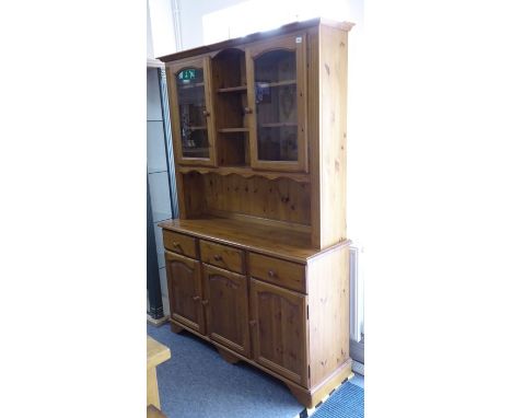 A modern pine dresser; the cornice above central shelf space and flanked by two glazed doors with further shelf space, three 