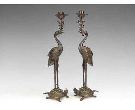 A pair of Japanese bronze candlesticks - modelled as cranes standing on tortoises, 32cm high.