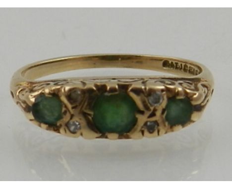 A 9 carat yellow gold, emerald, and diamond ring, set three graduated emeralds interspersed with diamonds. 