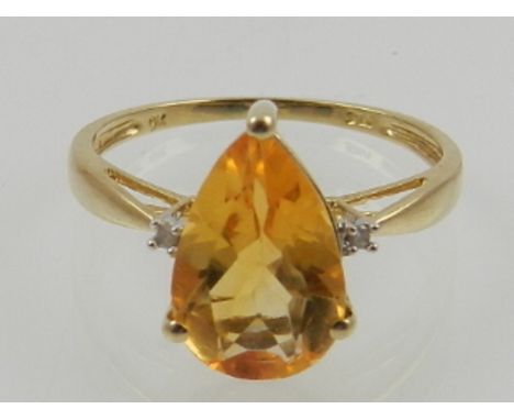 A 9 carat yellow gold and citrine ring, the pear cut citrine flanked by two diamond accents. 