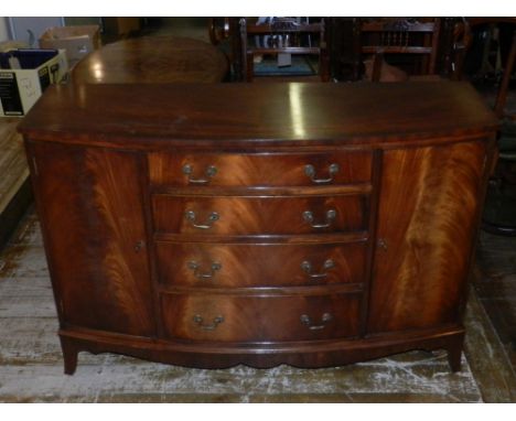 A George III style mahogany sideboard, with an arrangement of four drawers flanked by cupboards, above a shaped apron on brac