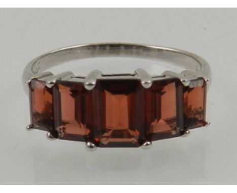 A 9 carat white gold and garnet ring, set five graduated rectangular garnets. 