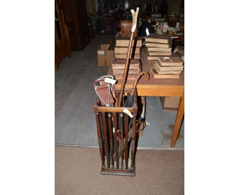 An early 20th Century oak umbrella stand with umbrellas, a stick and a shooting stick.