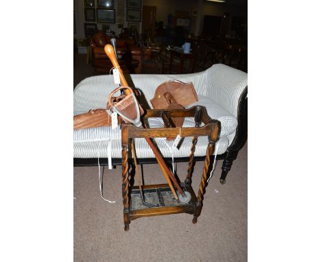 A stained oak umbrella receiver with barley twist supports, with walking stick, golf club and shooting stick.