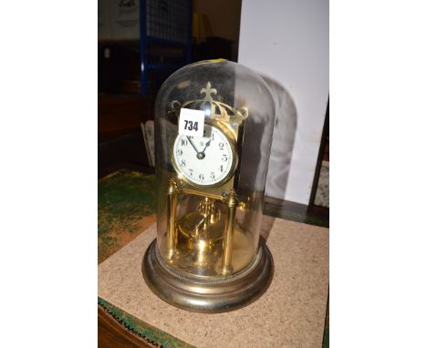 A brass perpetual motion mantel clock with arabic dial, under glass dome.