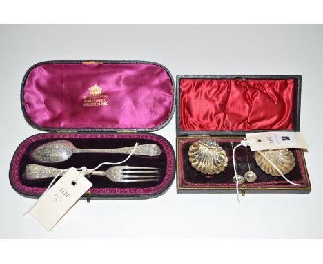 A pair of shell pattern silver table salts with spoons, in fitted case; together with a christening spoon and fork, also in f