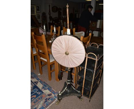 *A Regency ebonised pole screen, with circular silk panel on turned pole with reeded ball finial, the triform base raised on 