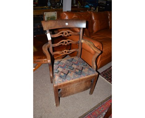 *A late Georgian mahogany open arm commode chair, with pierced ladder back and drop-in seat, raised on chamfered square legs 