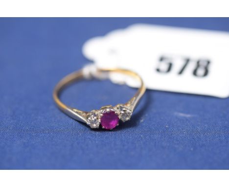 A ruby and diamond ring, the oval facet cut ruby flanked by brilliant cut diamonds, in white metal crown mounts above chenier