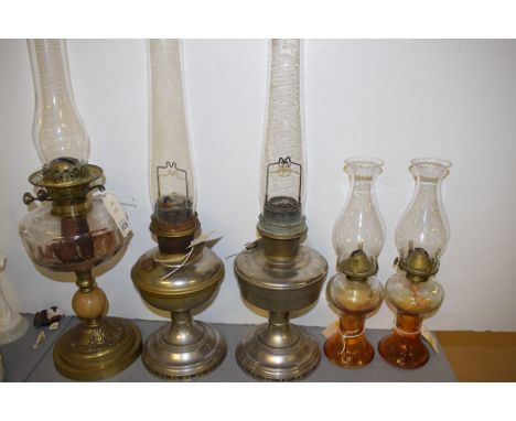 A Victorian oil lamp with brass reservoir, on marble and brass stand; a pair of chromed metal table oil lamps; and a pair of 