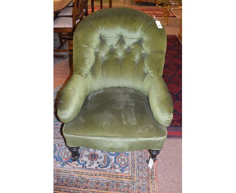a Victorian button back armchair upholstered in green velour raised on turned front legs terminating in ceramic castors.