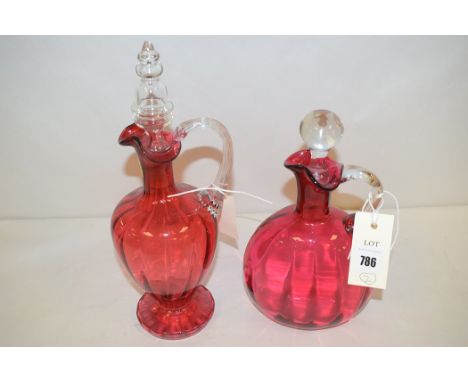 A Victorian cranberry glass oval flask with clear stopper; and another cranberry tinted decanter with clear stopper and handl