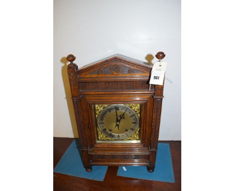 An early 20th Century eight day mantel clock, brass roman, with carved decoration to oak case.