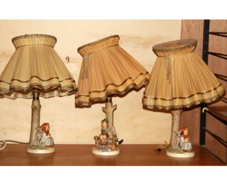 Three Hummel table lamp bases and shades.