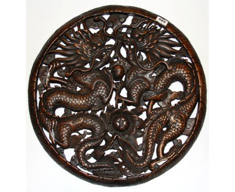 A circular Chinese carved hardwood panel decorated with two dragons, Dia. 58cm.