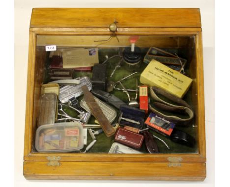 A pine display case and a collection of vintage barbers items, including a Prisoner of War razor, 60 x 64cm.