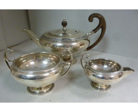 A three piece silver tea set of pedestal bowl design with cast vitruvian scrolled borders  comprising a teapot, having a swep