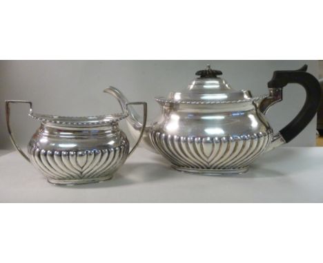 A silver teapot of oval, bulbous, demi-reeded form with a gadrooned rim, an S-shaped spout, an ebonised handle and knop to th